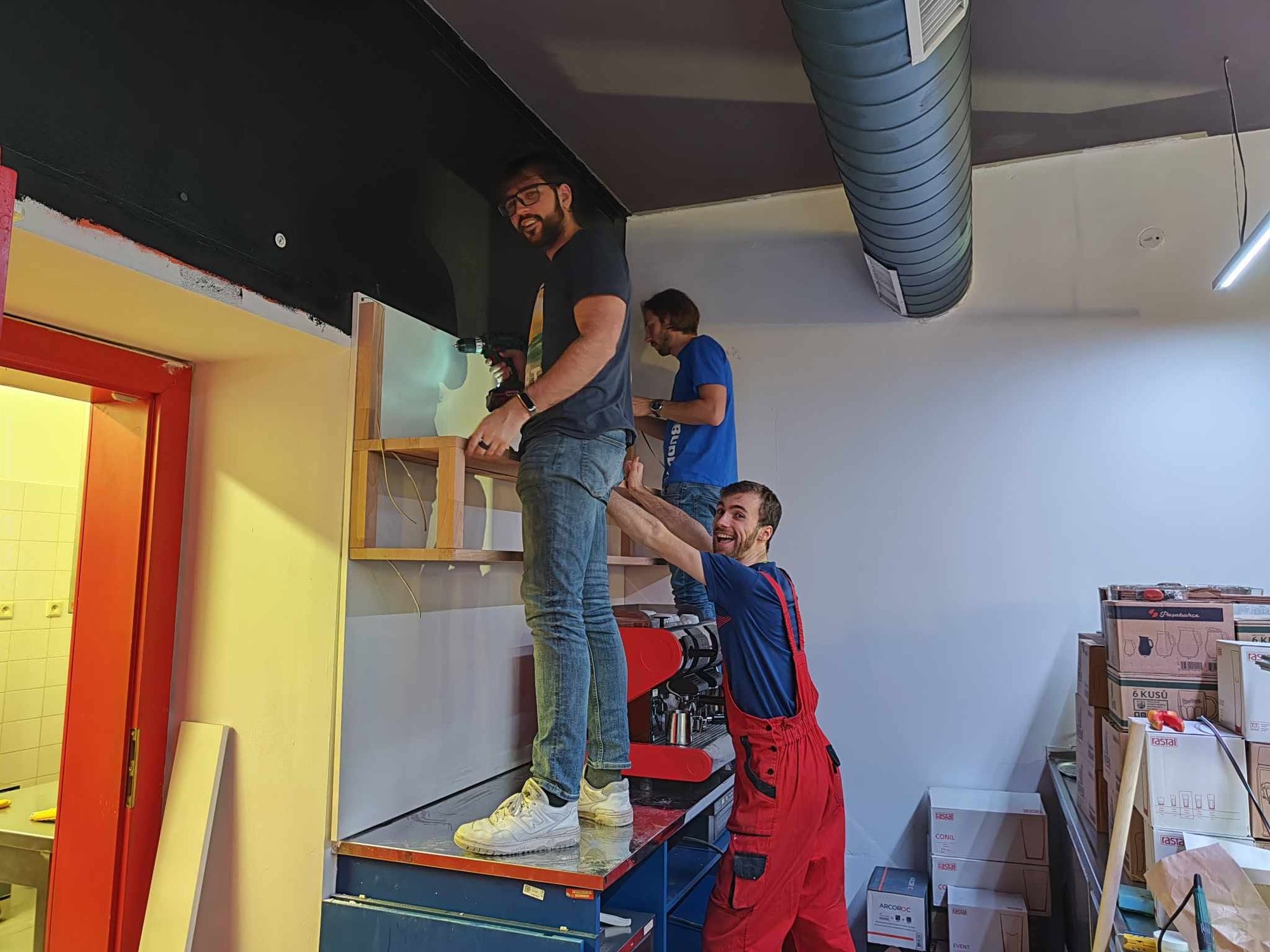 Two people on ladders painting the ceiling and wall