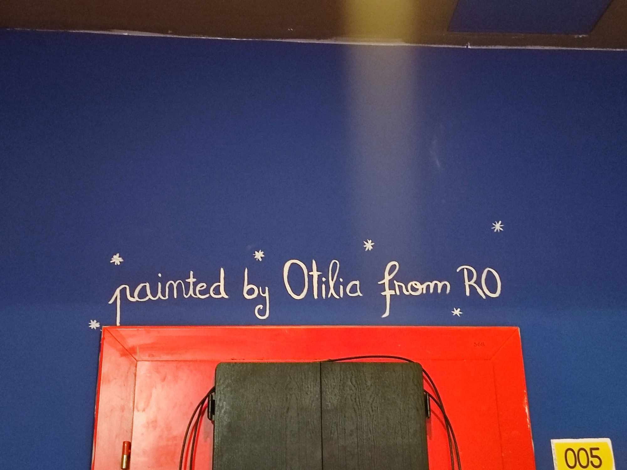 Handwriting on a red wall reading painted by Otilia from RO