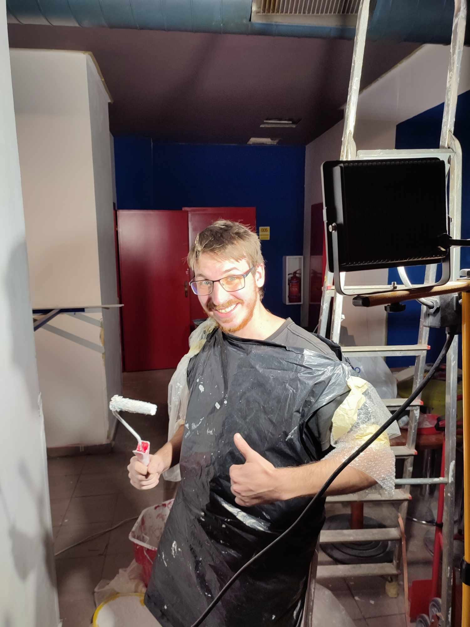 A painter in a plastic poncho giving a thumbs up, roller in hand